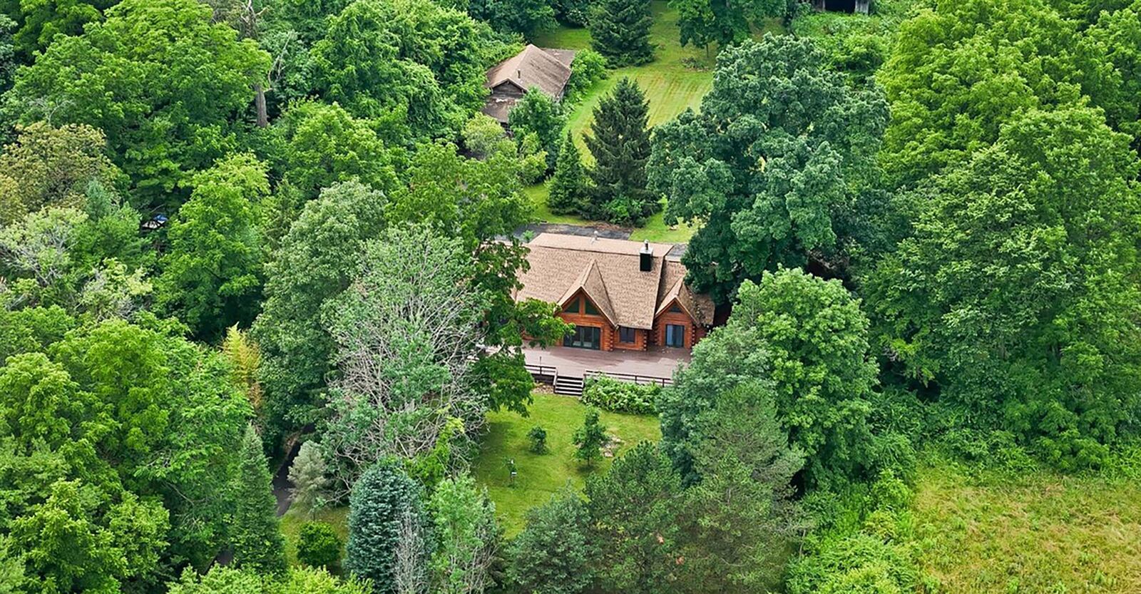 The rear of the home features an expansive wood deck across the back. The property also includes two barns/outbuildings.