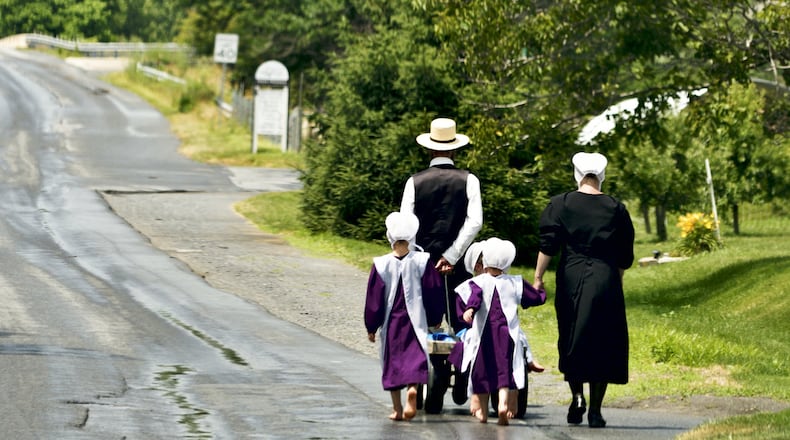 An Amish family walks bare feet over a country road. ISTOCK