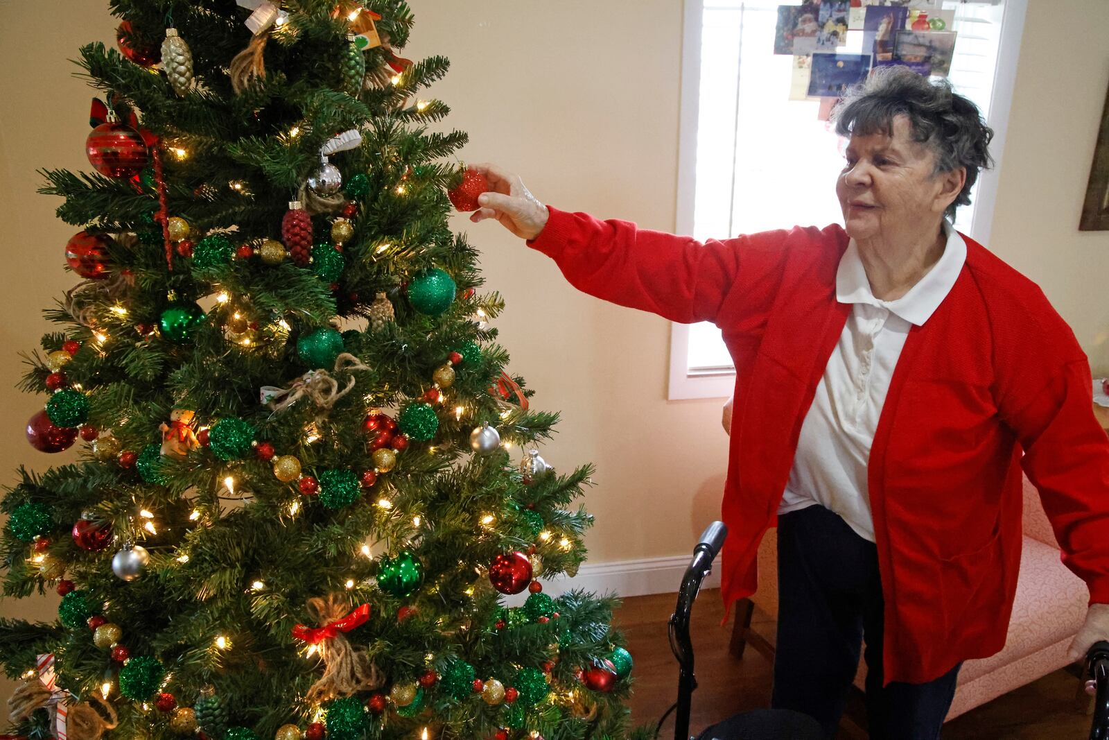 Clark Memorial Home resident,Shelby Rowe, helps decorate one of the Christmas trees in the Activity Room Wednesday, Dec. 6, 2023. BILL LACKEY/STAFF