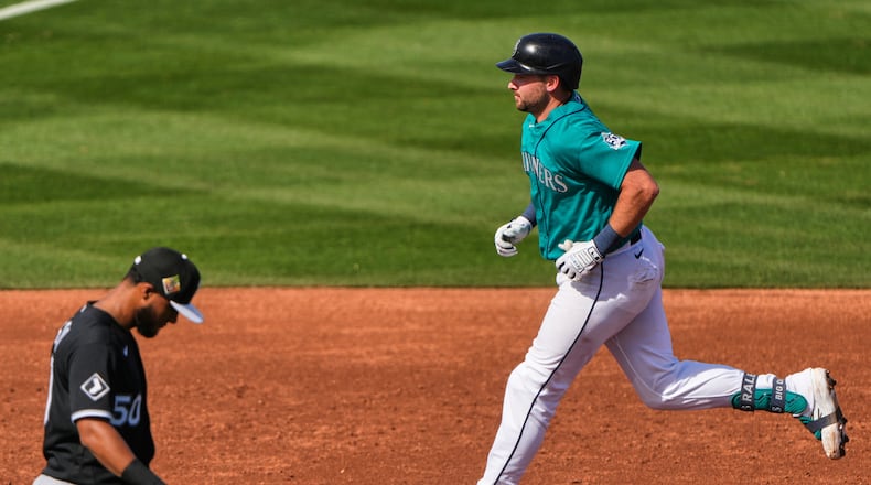 Seattle Mariners' Cal Raleigh runs the bases past Chicago White Sox third baseman Lenyn Sosa after hitting a two-run home run during the third inning of a spring training baseball game Tuesday, Feb. 24, 2026, in Peoria, Ariz. (AP Photo/Charlie Riedel)