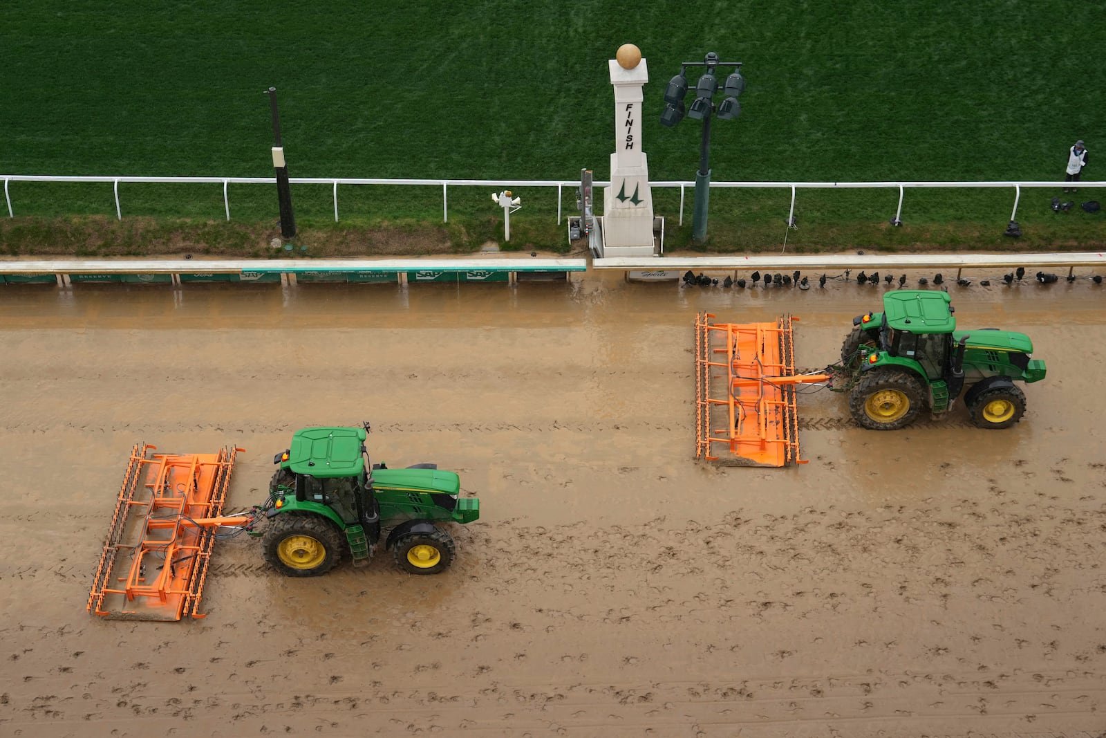 Tractors prepare the muddy track at Churchill Downs before the 151st running of the Kentucky Derby horse race Saturday, May 3, 2025, in Louisville, Ky. (AP Photo/Charlie Riedel)