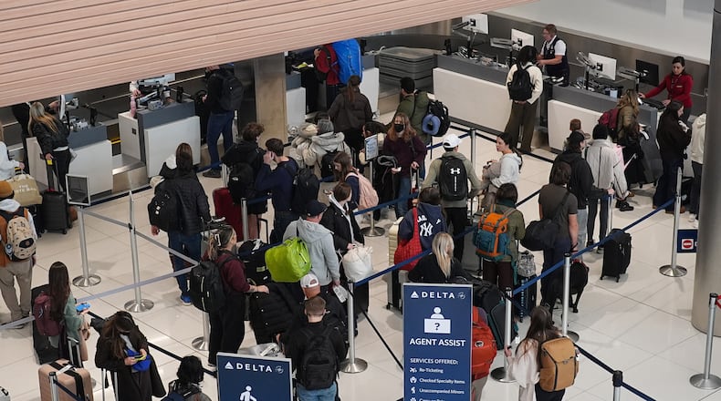 Travellers queue up at a check-in counter for Delta Airlines in Denver International Airport Friday, Dec. 19, 2025, in Denver. (AP Photo/David Zalubowski)