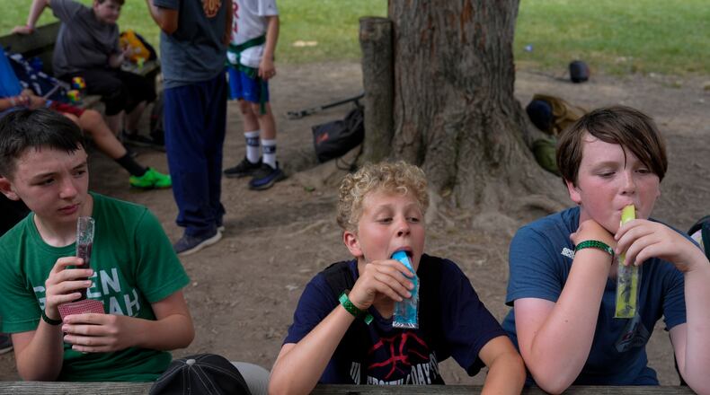 Campers eat popsicles while waiting at the zip line, Thursday, June 20, 2024, at YMCA Camp Kern in Oregonia, Ohio. As the first heat wave of the season ripples across the U.S., summer camps are working to keep their children cool while still letting the kids enjoy being outside with nature. (AP Photo/Joshua A. Bickel)
