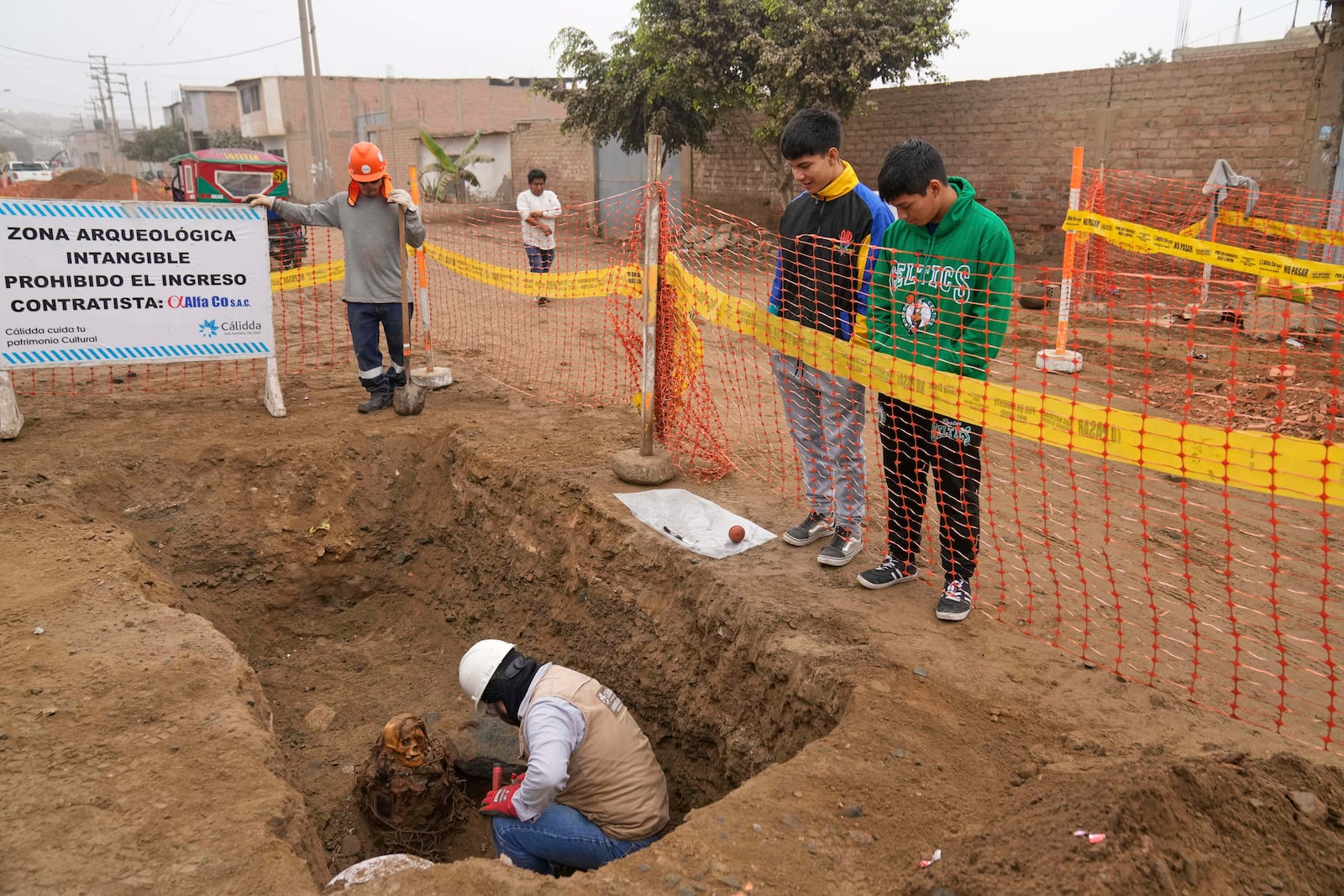 Archaeologist Jose Aliaga excavates an ancient mummy, which he said is a female from the pre-Inca Chancay culture, that was discovered by city workers who were digging a natural gas line for the company Calidda in the district of Puente Piedra on the outskirts of Lima, Peru, Wednesday, June 18, 2025. (AP Photo/Martin Mejia)