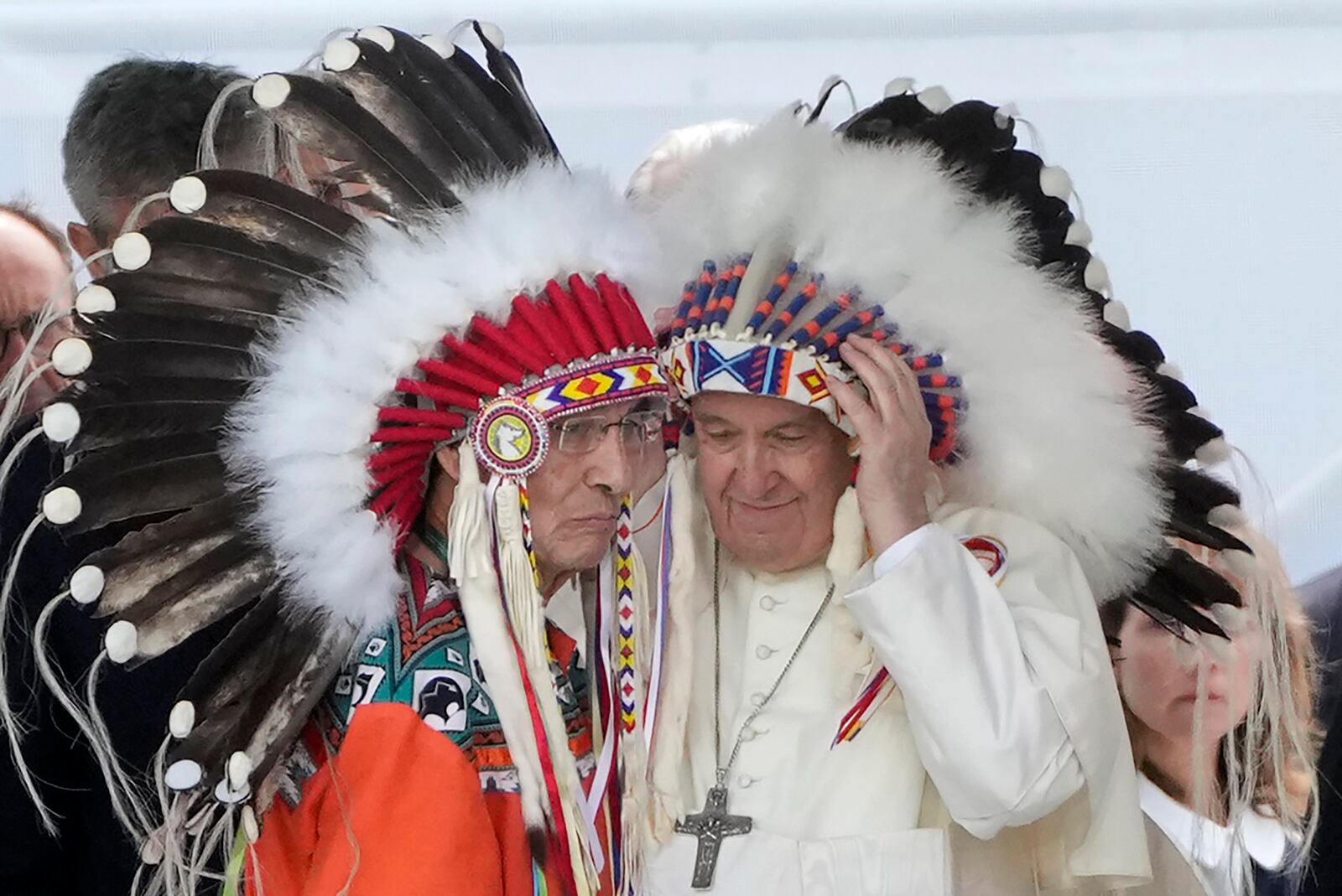 Pope Francis puts on an indigenous headdress during a meeting with indigenous communities, including First Nations, Metis and Inuit, at Our Lady of Seven Sorrows Catholic Church in Maskwacis, near Edmonton, Canada, Monday, July 25, 2022. Pope Francis begins a "penitential" visit to Canada to beg forgiveness from survivors of the country's residential schools, where Catholic missionaries contributed to the "cultural genocide" of generations of Indigenous children by trying to stamp out their languages, cultures and traditions. Francis set to visit the cemetery at the former residential school in Maskwacis. (AP Photo/Gregorio Borgia)