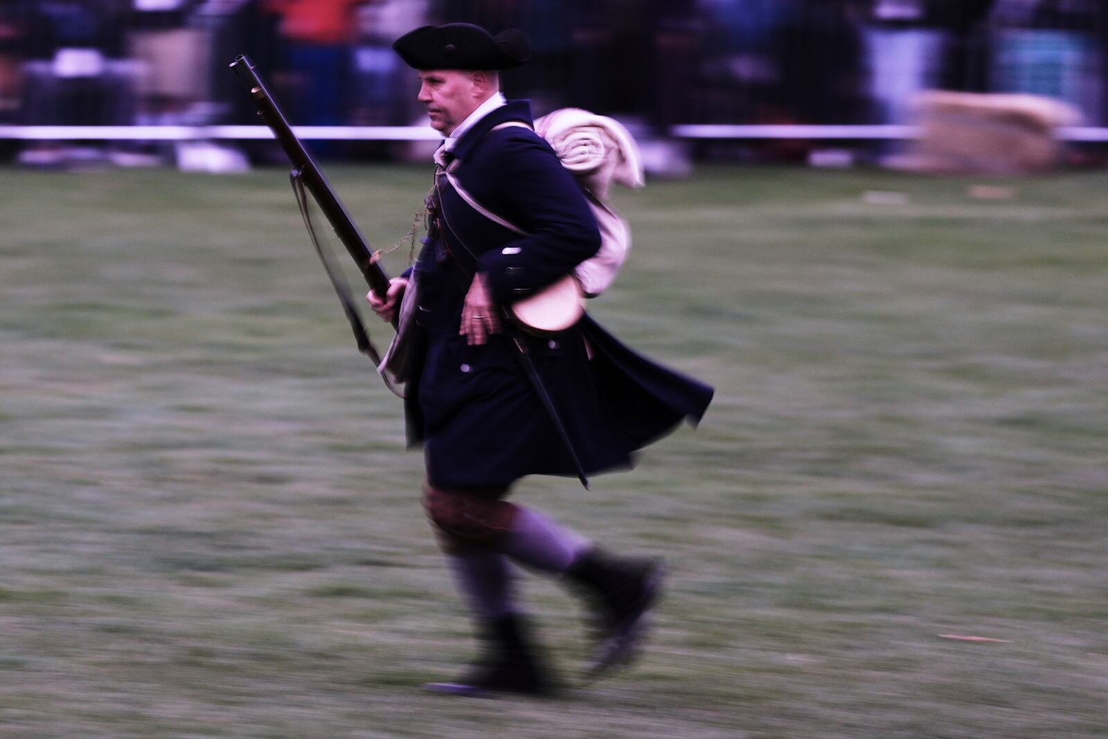 New England colonial militia man, also known as a Minuteman, runs towards fellow troops before sunrise during a reenactment celebration of the 250th anniversary of the Battle of Lexington and start of the American Revolution, Saturday, April 19, 2025, in Lexington, Mass. (AP Photo/Charles Krupa)