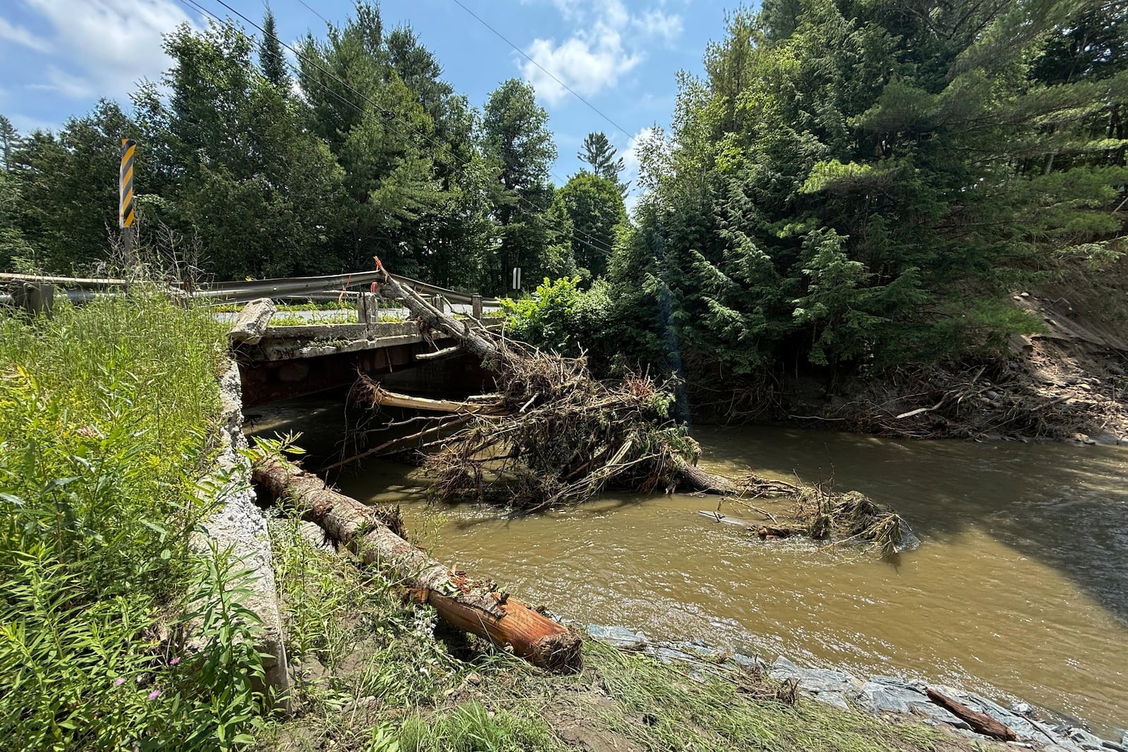 Damaged trees rest against a bridge after flash flooding in Sutton, Vt., Friday, July 11, 2025. (AP Photo/Amanda Swinhart)