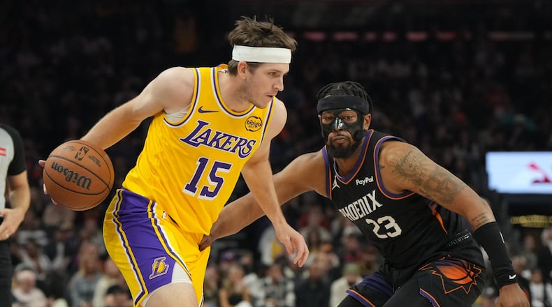 Los Angeles Lakers guard Austin Reaves shields the ball from Phoenix Suns guard Jordan Goodwin (23) during the first half of an NBA basketball game, Tuesday, Dec. 23, 2025, in Phoenix. (AP Photo/Rick Scuteri)
