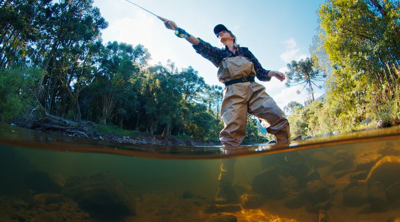 A woman fishing in a river. iSTOCK/COX