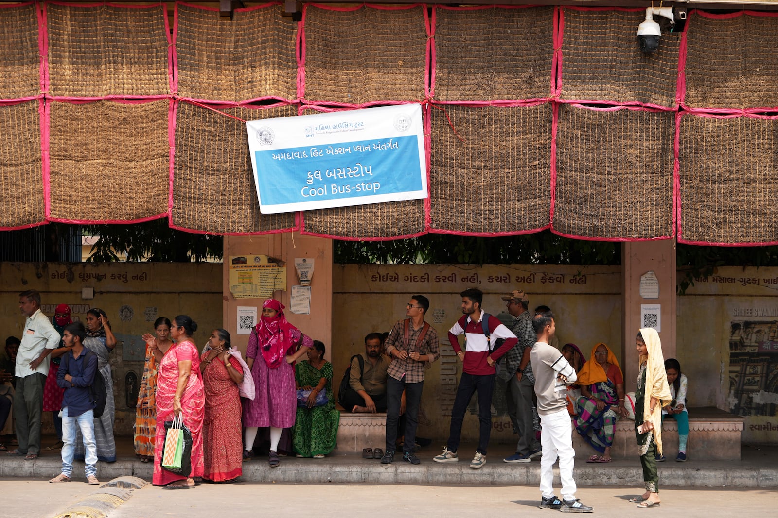 People wait for a bus at a cool bus stop in Ahmedabad, India, Wednesday, April 2, 2025. (AP Photo/Ajit Solanki)
