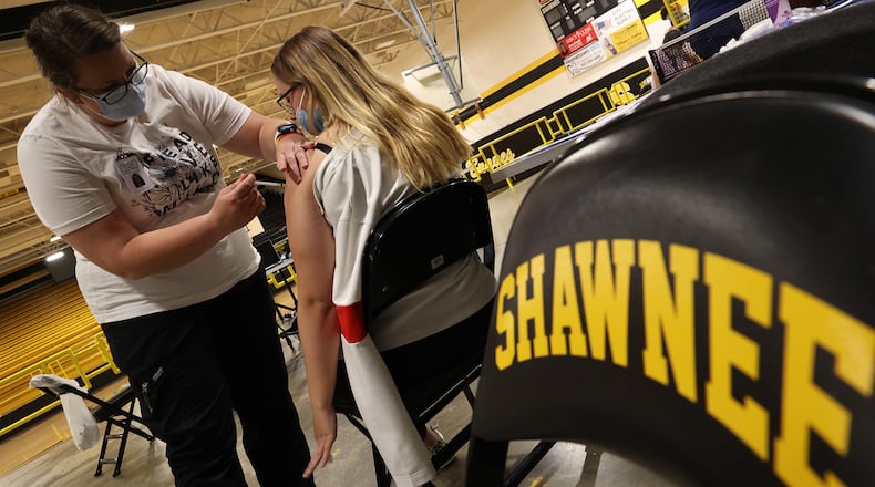 Nicole Wilson, a nurse at the Clark County Combined Health District, gives a student his COVID vaccine injection during a vaccine clinic at Shawnee High School. BILL LACKEY/STAFF