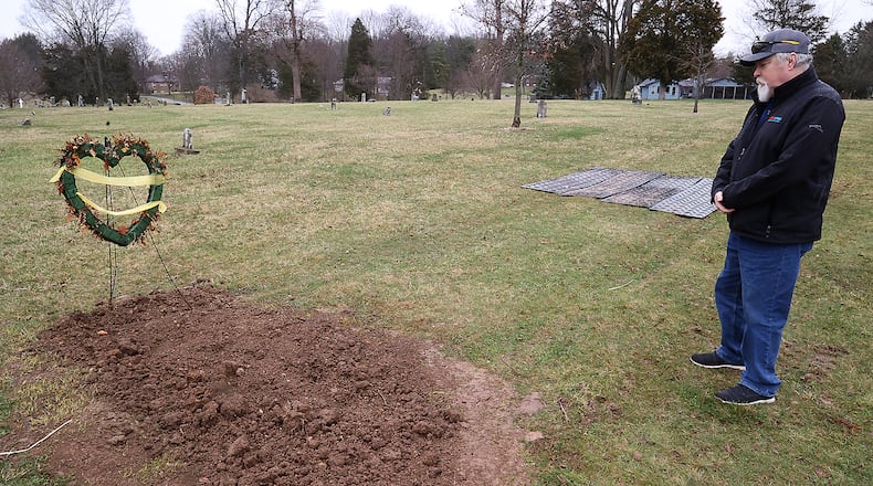 Lonnie Reynolds looks over the grave of his son Lonnie Reynolds, Jr. at Oak Dale Cemetery in Urbana Tuesday, March 22, 2022. The cemetery sold the elder Reynolds two plots at the cemetery and his son was buried in one. The cemetery now wants to exhume his son and rebury him because the plot was previously purchased by another family. BILL LACKEY/STAFF