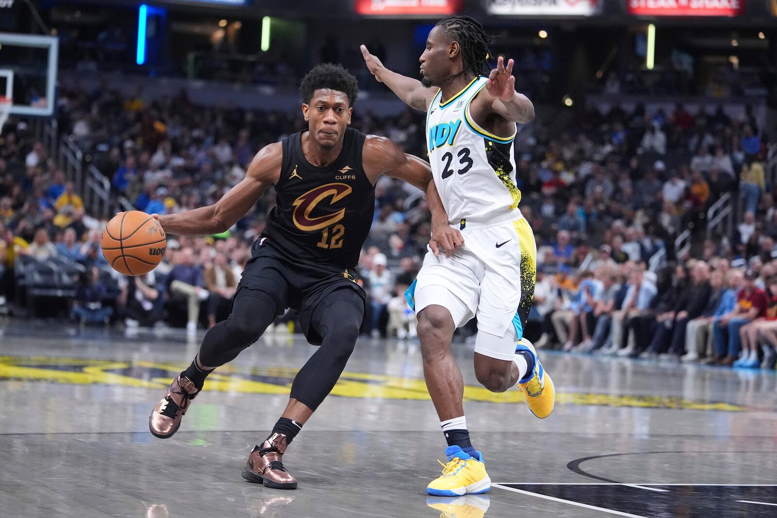 Cleveland Cavaliers forward De'Andre Hunter (12) drives on Indiana Pacers forward Aaron Nesmith (23) during the first half of an NBA basketball game in Indianapolis, Thursday, April 10, 2025. (AP Photo/Michael Conroy)