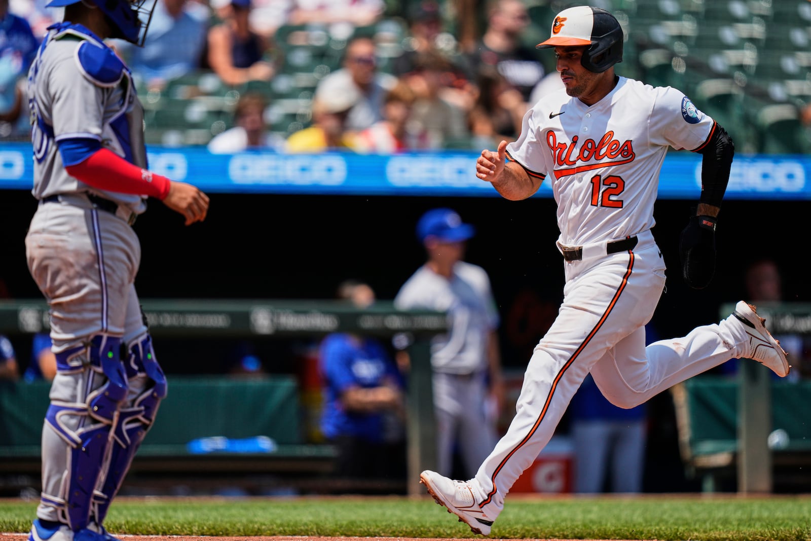 Baltimore Orioles' Ramon Laureano (12) scores past Toronto Blue Jays catcher Ali Sanchez, left, on a sacrifice fly hit by Cedric Mullins during the first inning in the first baseball game of a doubleheader, Tuesday, July 29, 2025, in Baltimore. (AP Photo/Stephanie Scarbrough)
