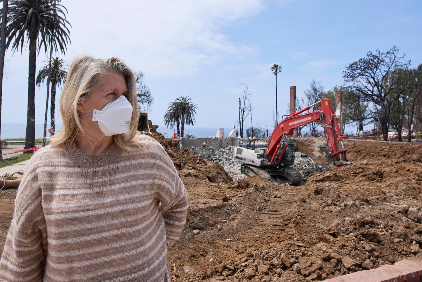 Pacific Palisades property owner DeAnn Heline stands in front of her home being rebuilt after the Palisades Fire in the Pacific Palisades section of Los Angeles, Thursday, April 24, 2025. (AP Photo/Damian Dovarganes)