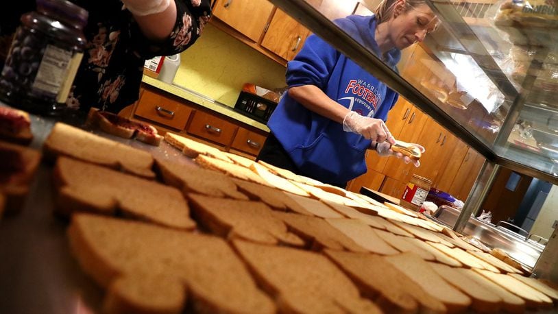 Erin Duke spreads the peanut butter for dozens of peanut butter and jelly sandwiches being assembled at H.O.P.E. Monday. H.O.P.E, a nonprofit organization, is providing students and families in need with lunch and dinner. BILL LACKEY/STAFF