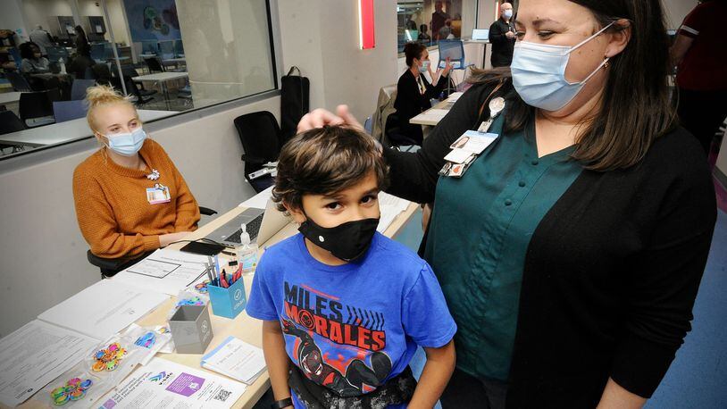 Roman Collier, age 10, waits with mother, Nikki, to receive his COVID-19 vaccine at Dayton Children's Monday, Nov. 8, 2021. MARSHALL GORBY\STAFF