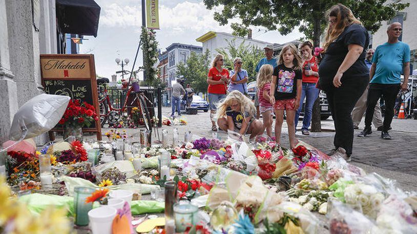 Mourners bring flowers to a makeshift memorial Tuesday, Aug. 6, 2019, for the slain and injured in the Oregon District after a mass shooting that occurred early Sunday morning in Dayton.