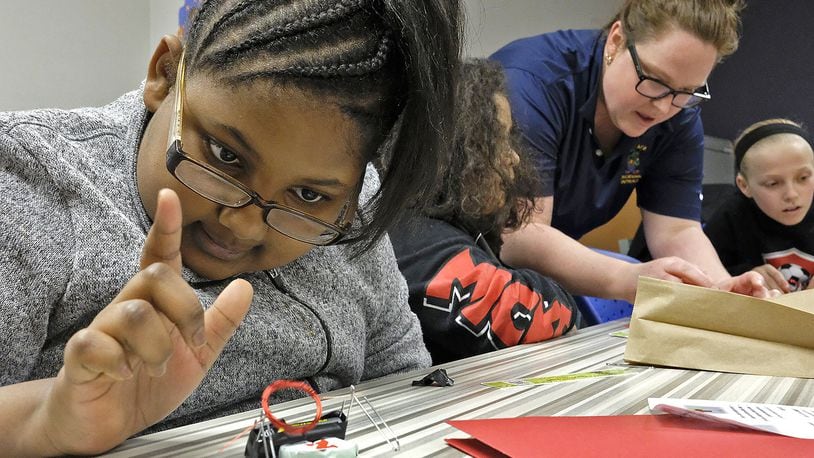 Jadie Welliford plays with the electric motor she made as Dr. Amanda King helps another student during one of the breakout sessions at the Springfield City Schools’ STEM program for girls. Bill Lackey/Staff