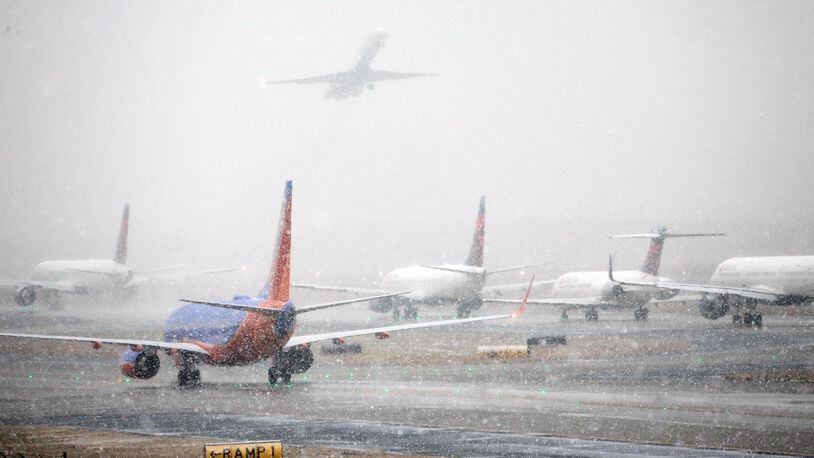 Planes line up on the tarmac as snow falls delaying travel at Hartsfield-Jackson Atlanta International Airport Friday, Dec. 8, 2017, in Atlanta. (Bob Andres/Atlanta Journal-Constitution via AP)