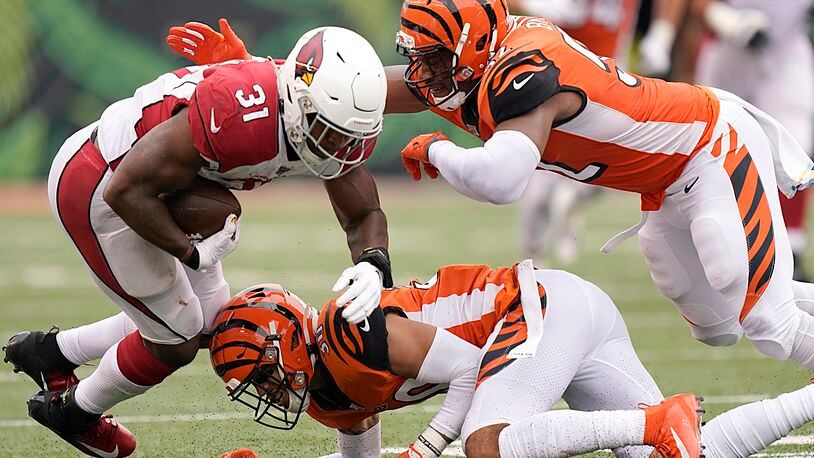 CINCINNATI, OHIO - OCTOBER 06: David Johnson #31 of the Arizona Cardinals is tackled by Preston Brown #52 and Jessie Bates #30 of the Cincinnati Bengals during the NFL football game at Paul Brown Stadium on October 06, 2019 in Cincinnati, Ohio. (Photo by Bryan Woolston/Getty Images)