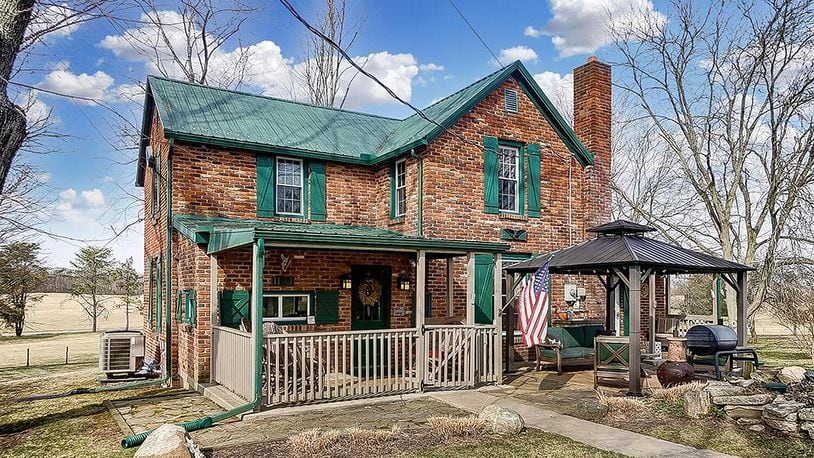 The all-brick farmhouse has 3 bedrooms and about 1,920 sq. ft. of living space. The home is on 5 acres and includes a 4-car, detached garage. The front of the home features mature trees, a covered front porch and gazebo covering a stone patio. CONTRIBUTED PHOTO