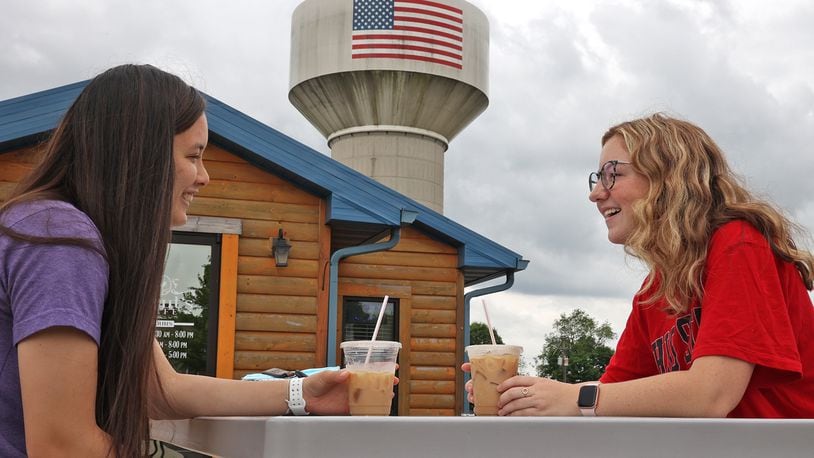 The Northridge Water Tank looms over Emma Randall, left, and Cassie Pencil as they enjoy their cold beverages outside Scouts Cafe. BILL LACKEY/STAFF