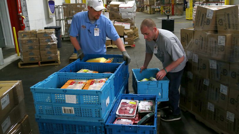 Garrett Wallen, left, and Andrew Venneman, of the Second Harvest Food Bank, stack food on a pallet in the warehouse. Northeastern FFA is partnering with the food bank. Bill Lackey/Staff