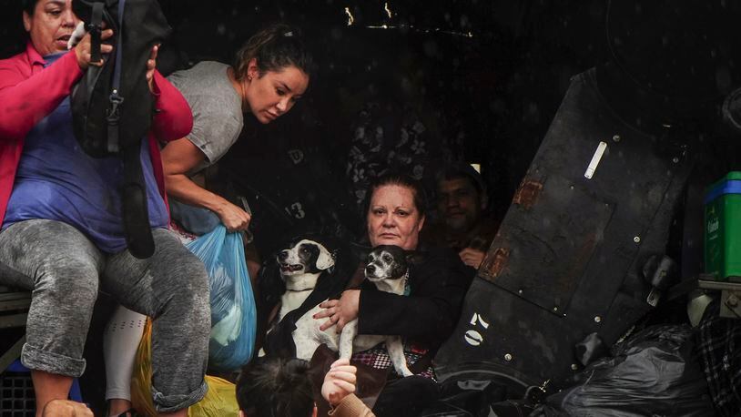 People and their pets evacuate a flooded area after heavy rain in Sao Sebastiao do Cai, Rio Grande do Sul state, Brazil, Thursday, May 2, 2024. (AP Photo/Carlos Macedo)