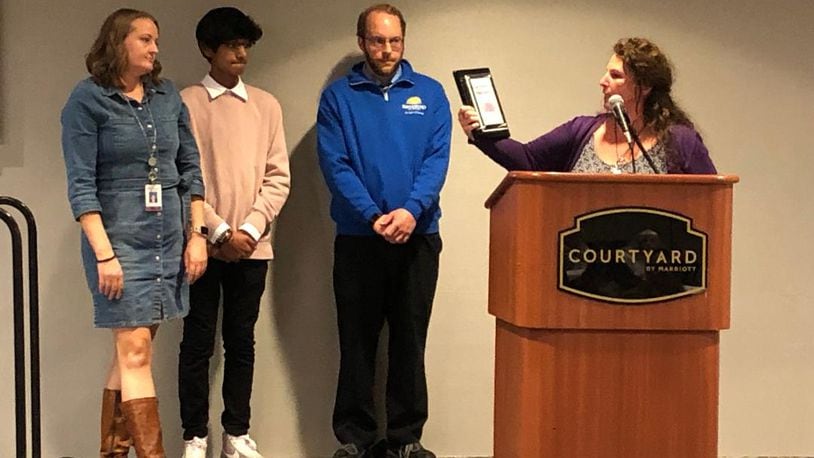 Project Woman executive director Laura Baxter, right, and colleague Audrey Ferryman, left, present the organization's Purple Ribbon Award for service and volunteerism to the organization to Ridgewood School student council president Mahed Rizvi and teacher and student council advisor Dan Metzger during a ceremony on Wednesday afternoon.