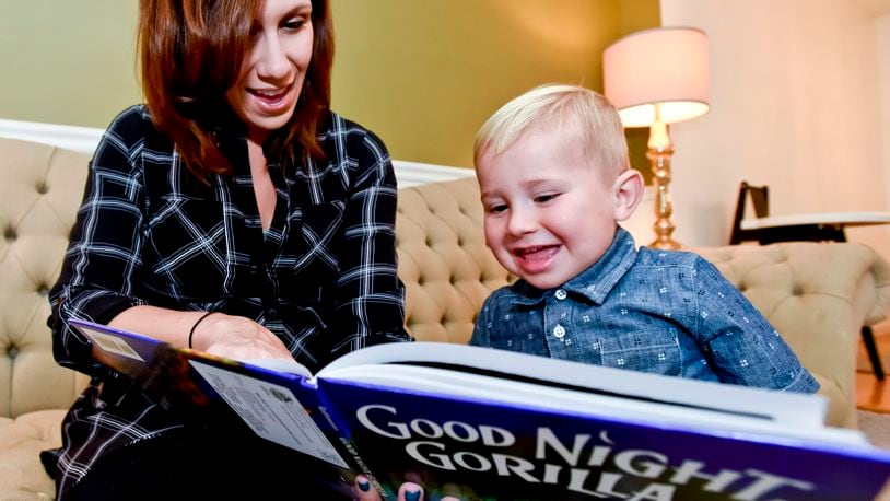 Sara Flynn reads a book from the Dolly Parton Imagination Library to her son Theo at her home in Middletown. The program is expanding to include Clark County. NICK GRAHAM/STAFF