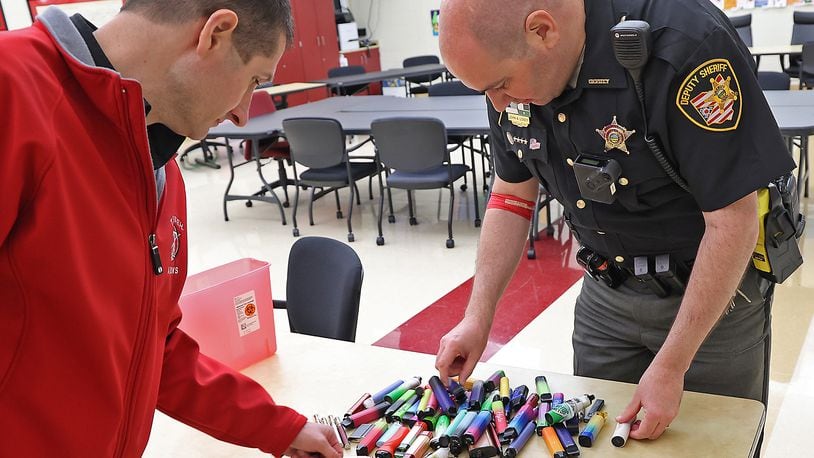 Brian Dixon, director of Safety at Tecumseh Local Schools, and Deputy John Loney, the school's resource officer, look through some of the vape pens that have been confiscated from students in this 2022 image. The Clark County Combined Health District has seen an increase in vaping -- with some as young as fifth grade -- and has developed a five-year strategic plan to bring the numbers down.  BILL LACKEY/STAFF