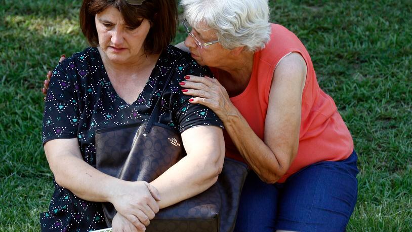 Jonell Payton, right, comforts Lisa Dew, outside the Durant, Miss., home of two slain Catholic nuns, Thursday, Aug. 25, 2016. The nuns worked as nurses at the Lexington Medical Clinic, where Dew was the office manager. Dew and a Durant police officer discovered their bodies inside the house after both nuns did not report for work. (AP Photo/Rogelio V. Solis)