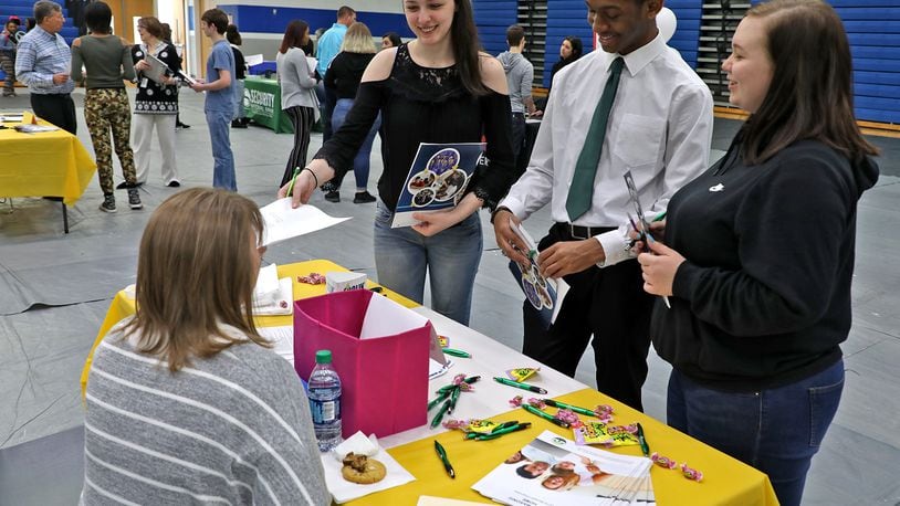 Heaven Kuhn, left, a senior at Springfield High School, hands her resume to Lynette Newton, from The Ohio Masonic Community, as Kuhn and fellow seniors Fred Almon and Madison Brown talk to Newton about employment opportunities at the school’s second annual Career Fair in April. More than 20 local employers were on hand to talk with over 150 students about career opportunities locally. BILL LACKEY/STAFF