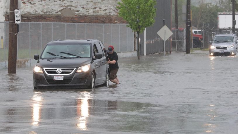 A stranger helps a man by pushing him out of the high water on North Street in Springfield. BILL LACKEY/STAFF