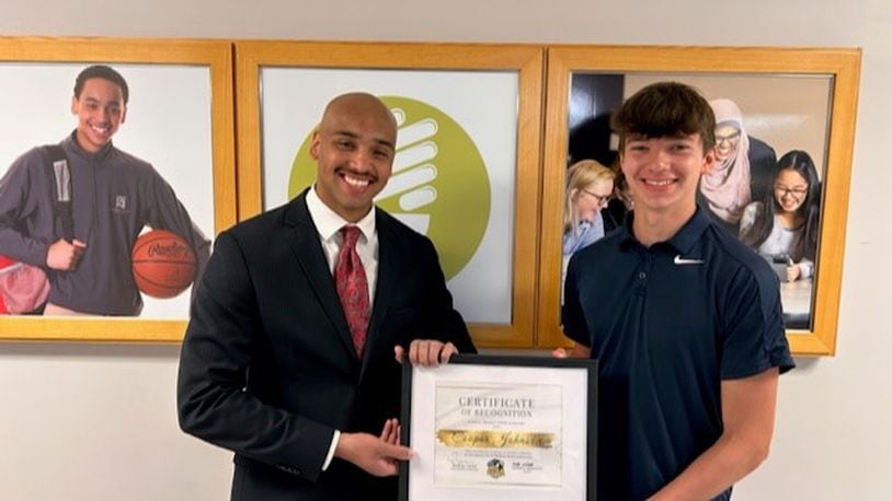 Cooper Johnson (right), a graduate of the Global Impact STEM Academy Class of 2023, was awarded the first Waklatsi Service Scholarship, which was established this year by GISA alumnus and current Clark County Sheriff's Deputy Kordell Waklatsi (left), with a picture behind him of when he was a freshman student. Contributed