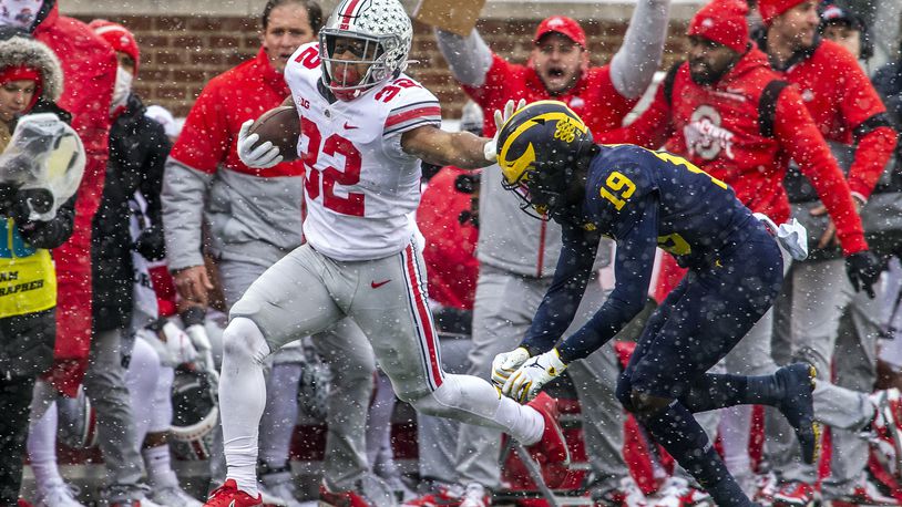 Ohio State running back TreVeyon Henderson (32) tries to fend off Michigan defensive back Rod Moore (19) in the first quarter of an NCAA college football game in Ann Arbor, Mich., Saturday, Nov. 27, 2021. (AP Photo/Tony Ding)