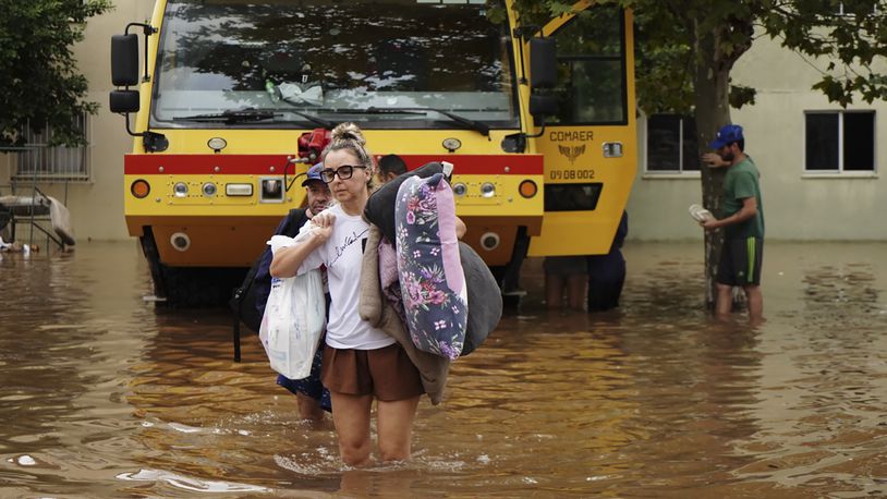 Residents evacuate from a neighborhood flooded by heavy rains, in Canoas, Rio Grande do Sul state, Brazil, Saturday, May 4, 2024. (AP Photo/Carlos Macedo)