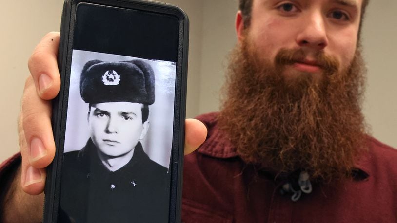 David Kravets, a music teacher at Springfeld High School, holds up a black and white picture of his Ukrainian father on his phone Wednesday, April 13, 2022. The photo was taken when his father was in the Red Army when Ukraine was part of the Soviet Union. BILL LACKEY/STAFF