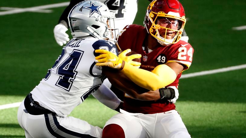 Washington Football Team running back Antonio Gibson (24) is stopped on a carry by Dallas Cowboys cornerback Chidobe Awuzie, left, in the first half of an NFL football game in Arlington, Texas, Thursday, Nov. 26, 2020. (AP Photo/Roger Steinman)