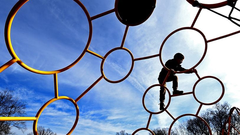 A child plays on the playground at Smith Park in New Carlisle Monday as he and his family take advantage of the unseasonably warm temperatures and sunshine. BILL LACKEY/STAFF