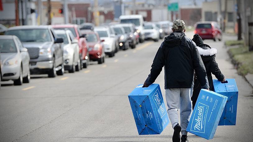 Bobby and Carolyn Allen carry their cases of Mikesell's potato chips down Stanley Avenue to the car that they parked down the block Thursday March 2, 2023. MARSHALL GORBY \STAFF