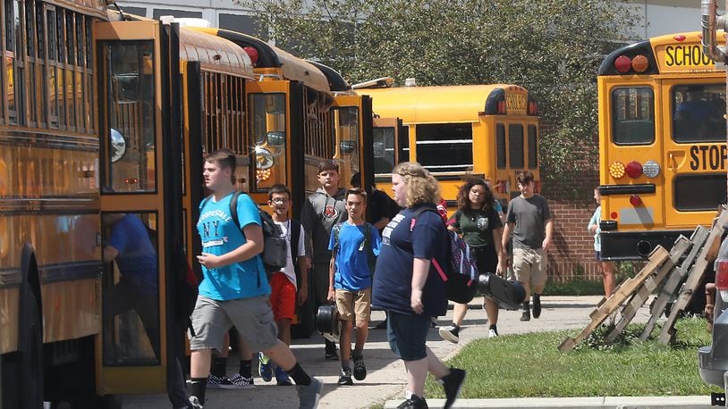 Students board school bus outside Shawnee High School a little over a year ago. This year, bus transportation will still be available, but districts are encouraging parents to transport their children to and from school. BILL LACKEY/STAFF